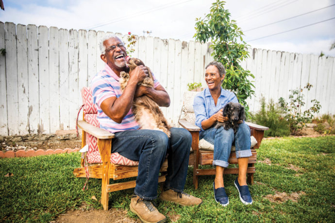 A senior couple playing outdoors with their two dachshunds.