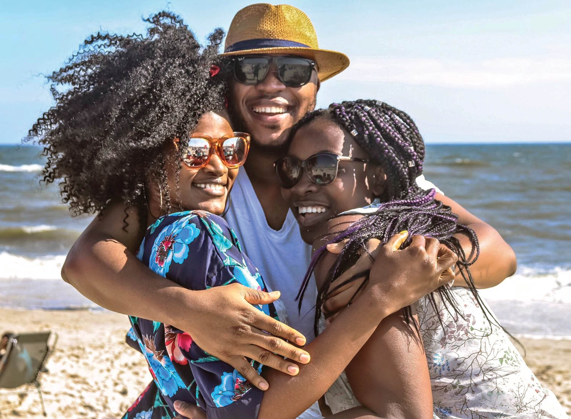 Three friends hugging on the beach.