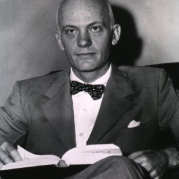 Vintage photo of a man with a bowtie reading a book.