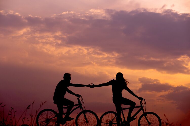 Two people riding bicycles at sunset.
