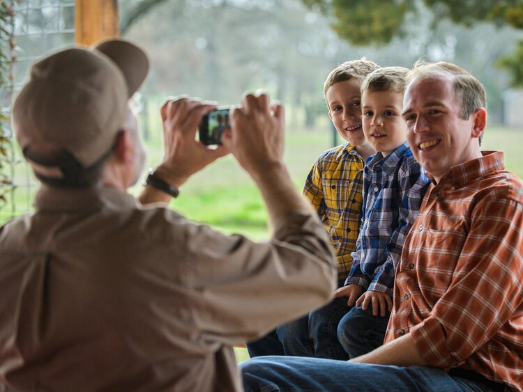 Man taking a picture of a man and his sons.